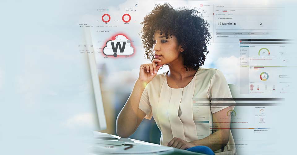 Schwarze Frau mit natürlich gelocktem Haar in einem weißen Seidentop schaut auf einen Monitor. Im Hintergrund sind WatchGuard Cloud-Bildschirme zu sehen.