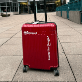 Valise rigide rouge ornée d'autocollants WatchGuard et Security That Travels (la sécurité embarquée)