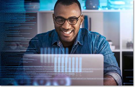 Smiling black man in glasses looking at a laptop